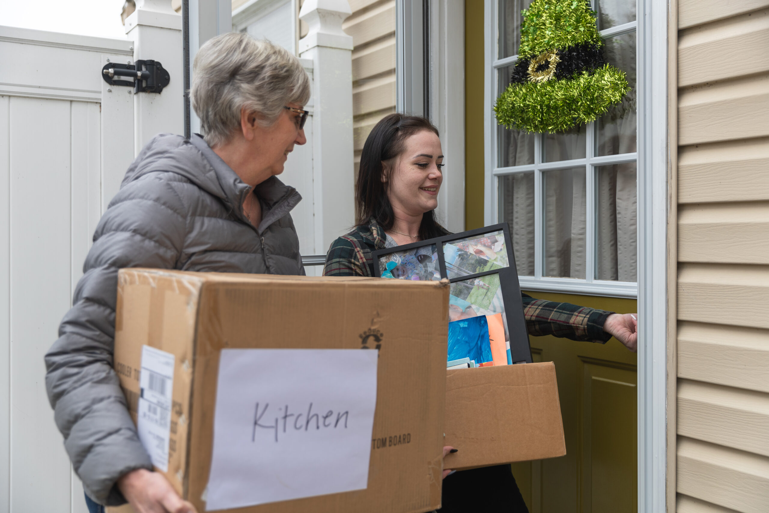 A mom opening the front door to her new house with a Neighboring Volunteer helping her move in.